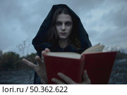 hooded man looking camera with blurred book. Стоковое фото, агентство Ingram Publishing / Фотобанк Лори