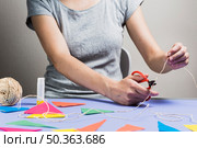 woman hand cutting string with scissor during making bunting. Стоковое фото, агентство Ingram Publishing / Фотобанк Лори