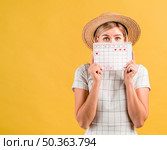 young woman with hat covering her face with menstruation calendar. Стоковое фото, агентство Ingram Publishing / Фотобанк Лори