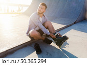 young man putting rollerskates skate park. Стоковое фото, агентство Ingram Publishing / Фотобанк Лори