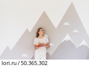 young woman holding book standing against graffiti wall. Стоковое фото, агентство Ingram Publishing / Фотобанк Лори