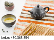 chinese clay teapot with floral blooming tea ball tea cup against white backdrop. Редакционное фото, агентство Ingram Publishing / Фотобанк Лори