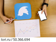 person holding mobile phone analyzing twitter graph. Стоковое фото, агентство Ingram Publishing / Фотобанк Лори