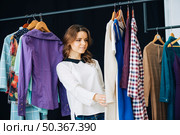 woman looking dresses clothes rail. Стоковое фото, агентство Ingram Publishing / Фотобанк Лори