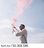 black man holding red smoke bombs. Стоковое фото, агентство Ingram Publishing / Фотобанк Лори