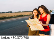 women standing near white car looking map. Стоковое фото, агентство Ingram Publishing / Фотобанк Лори