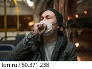 front view sick man coughing bus while wearing medical mask. Стоковое фото, агентство Ingram Publishing / Фотобанк Лори