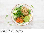 Oatmeal with salted salmon, avocado guacamole and fresh vegetable salad of arugula, cucumbers and olives. Breakfast. Top view. Стоковое фото, агентство Ingram Publishing / Фотобанк Лори