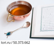 OLYMPUS DIGITAL CAMERA. close up opened quran with tea cup. Редакционное фото, агентство Ingram Publishing / Фотобанк Лори