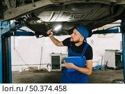 mechanic checking bottom car. Стоковое фото, агентство Ingram Publishing / Фотобанк Лори