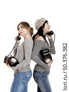 Two young women talking with old telephones - Isolated on white. Стоковое фото, агентство Ingram Publishing / Фотобанк Лори