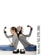 Two young women talking with old telephones - Isolated on white. Стоковое фото, агентство Ingram Publishing / Фотобанк Лори