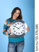 Woman holding a clock on a blue background. Стоковое фото, агентство Ingram Publishing / Фотобанк Лори