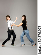 Two young beautiful sisters having fun simulating a fight  - This models are true twins. Стоковое фото, агентство Ingram Publishing / Фотобанк Лори