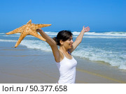 Beautiful woman on the beach felling the breeze with a starfish on the hand. Стоковое фото, агентство Ingram Publishing / Фотобанк Лори