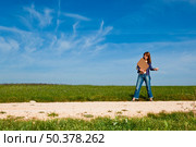 Young woman hitch hiking on a beautiful green meadow. Стоковое фото, агентство Ingram Publishing / Фотобанк Лори