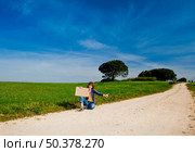 Young woman hitch hiking on a beautiful green meadow. Стоковое фото, агентство Ingram Publishing / Фотобанк Лори