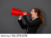 Business young woman speaking to a megaphone, over a grey background. Стоковое фото, агентство Ingram Publishing / Фотобанк Лори
