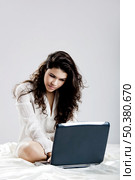 Beautiful young woman on bed working with a laptop. Стоковое фото, агентство Ingram Publishing / Фотобанк Лори