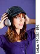 Beautiful and happy young woman listen music with headphones, over a violet background. Стоковое фото, агентство Ingram Publishing / Фотобанк Лори
