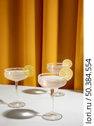 glass margarita cocktail garnish with lime table against yellow curtain. Стоковое фото, агентство Ingram Publishing / Фотобанк Лори