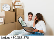 young happy couple holding picture frame hand with moving boxes new home. Стоковое фото, агентство Ingram Publishing / Фотобанк Лори