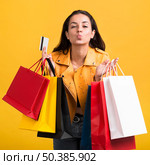young woman yellow leather jacket with shopping bags. Стоковое фото, агентство Ingram Publishing / Фотобанк Лори