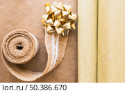 elevated view weaving ribbon golden bow with shiny gift paper. Стоковое фото, агентство Ingram Publishing / Фотобанк Лори