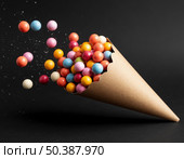 Kraft paper bag with scattered dragee candies on black background. Стоковое AI-изображение, AI-художник Анна Никонорова / Фотобанк Лори