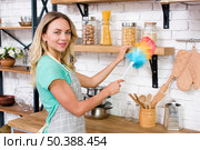 smiling woman looking camera while dusting kitchen. Стоковое фото, агентство Ingram Publishing / Фотобанк Лори