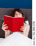 Beautiful young woman reading a book with a astonish expression. Стоковое фото, агентство Ingram Publishing / Фотобанк Лори