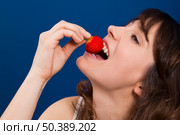 Beautiful and happy young woman eating a strawberry with taste. Стоковое фото, агентство Ingram Publishing / Фотобанк Лори