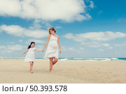 Beautiful pregnant woman and her little daughter walking on the beach. Стоковое фото, агентство Ingram Publishing / Фотобанк Лори