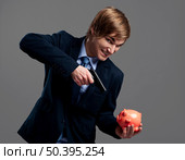 Businessman holding and pointing a gun to a piggy bank. Стоковое фото, агентство Ingram Publishing / Фотобанк Лори