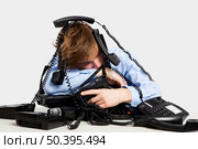 Exhausted man sitting with a bunch of phones over him. Стоковое фото, агентство Ingram Publishing / Фотобанк Лори