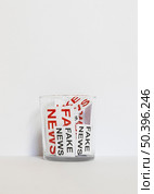 glass with paper sheet with fake news. Стоковое фото, агентство Ingram Publishing / Фотобанк Лори