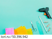 overhead view yellow pink paper scissor ruler pencil clothespins electric glue gun turquoise background. Стоковое фото, агентство Ingram Publishing / Фотобанк Лори