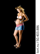 Beautiful and young pregnant woman holding a head-phones over her belly to the baby can listen music. Стоковое фото, агентство Ingram Publishing / Фотобанк Лори