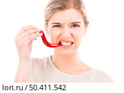 Beautiful girl making a silly face biting a red chilli pepper, isolated over a white background. Стоковое фото, агентство Ingram Publishing / Фотобанк Лори