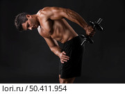 Portrait of a muscular man lifting weights against a dark background. Стоковое фото, агентство Ingram Publishing / Фотобанк Лори