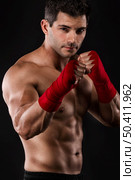 Portrait of a muscular man practicing body combat against a dark background. Стоковое фото, агентство Ingram Publishing / Фотобанк Лори
