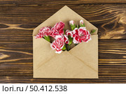 brown envelope with red carnation flowers wooden desk. Стоковое фото, агентство Ingram Publishing / Фотобанк Лори