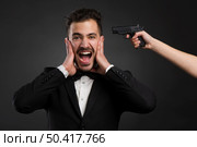 Man yelling with a weapon pointing on his head . Стоковое фото, агентство Ingram Publishing / Фотобанк Лори