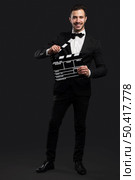 Studio portrait of a fashion young man wearing a suit and holding a clapboard. Стоковое фото, агентство Ingram Publishing / Фотобанк Лори