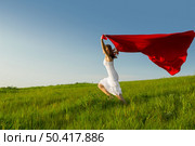 Young beautiful woman running while holding a red tissue. Стоковое фото, агентство Ingram Publishing / Фотобанк Лори