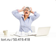 Stressed elderly woman working in the office with a laptop. Стоковое фото, агентство Ingram Publishing / Фотобанк Лори