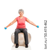 Happy fitness old woman lifting dumbbells while sitting over a PIlates ball. Стоковое фото, агентство Ingram Publishing / Фотобанк Лори