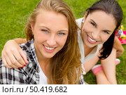 Teens best friends sitting on the grass smiling and having a good time. Стоковое фото, агентство Ingram Publishing / Фотобанк Лори