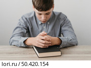 boy praying with his hands bible. Стоковое фото, агентство Ingram Publishing / Фотобанк Лори