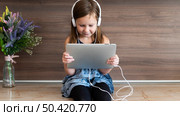 front view smiley girl using tablet with headphones. Стоковое фото, агентство Ingram Publishing / Фотобанк Лори